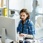 Junger Mann arbeitet konzentriert am Computer in einem Büro