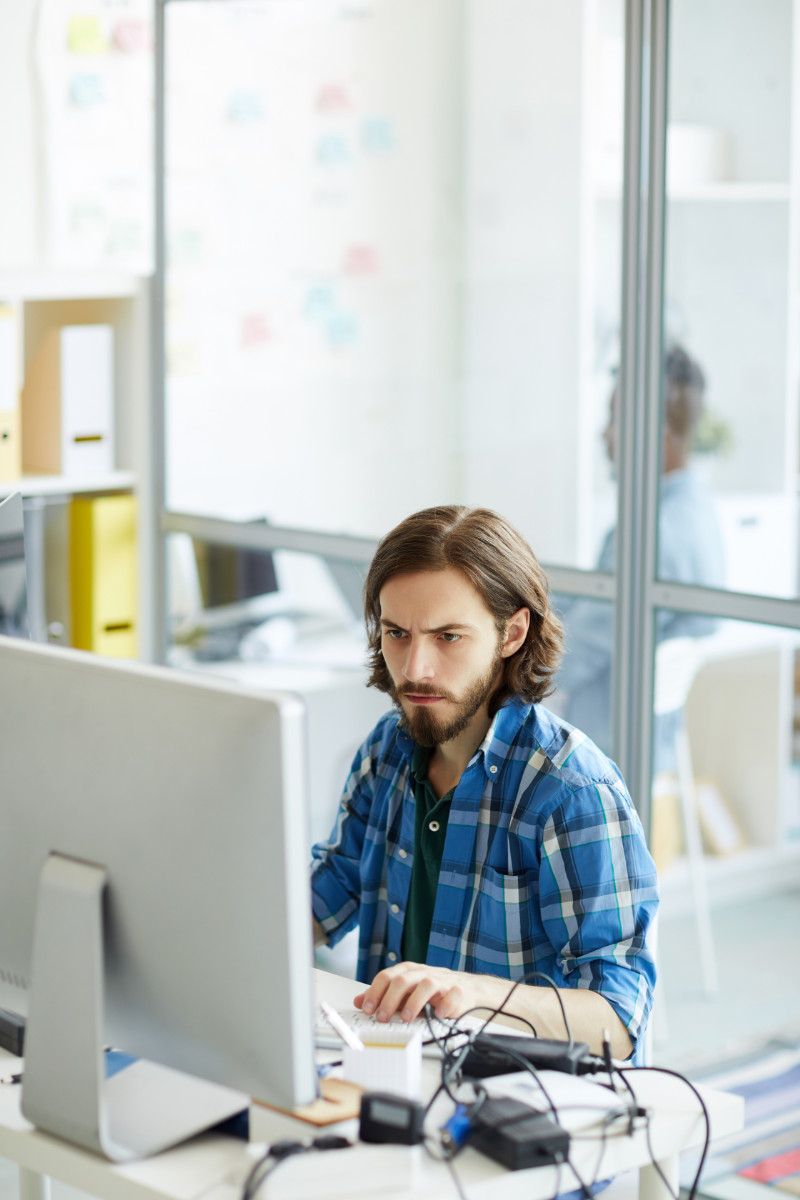 Junger Mann arbeitet konzentriert am Computer in einem B&uuml;ro